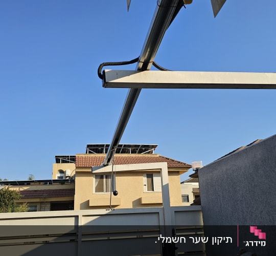 שער חשמלי עם מנגנון פתיחה על רקע שמיים כחולים
